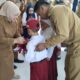 Wakil Bupati Tojo Una-Una, Surya, secara simbolis menyerahkan bantuan pakaian seragam sekolah kepada salah satu peserta didik baru jenjang SD, dalam acara penyerahan bantuan di Aula SMP Negeri 2 Ratolindo, Senin (6/7/2026).