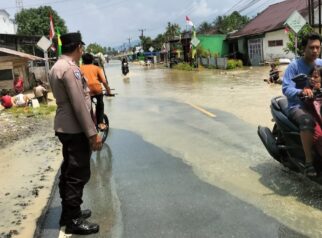 Personel Polsek Kasimbar mengatur lalu lintas dan memberikan arahan keselamatan kepada pengguna jalan saat melintas di Jalan Trans Sulawesi, Desa Sendana, Minggu (16/8/2026).